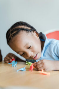 young primary school child playing with dinosaur figurines