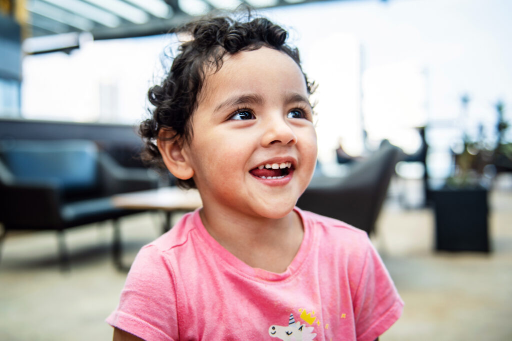 young child in pink t-shirt smiling and looking up