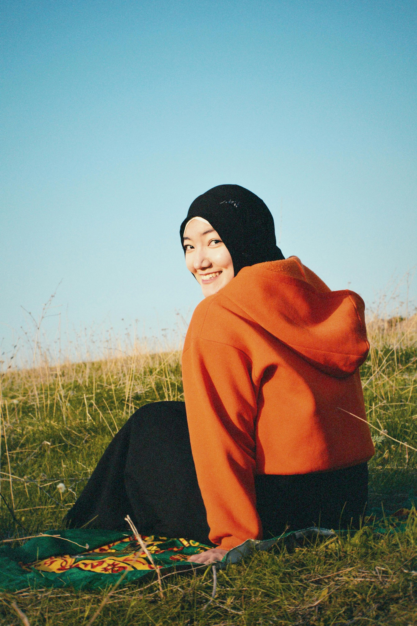 young smiling woman sitting outside on grass
