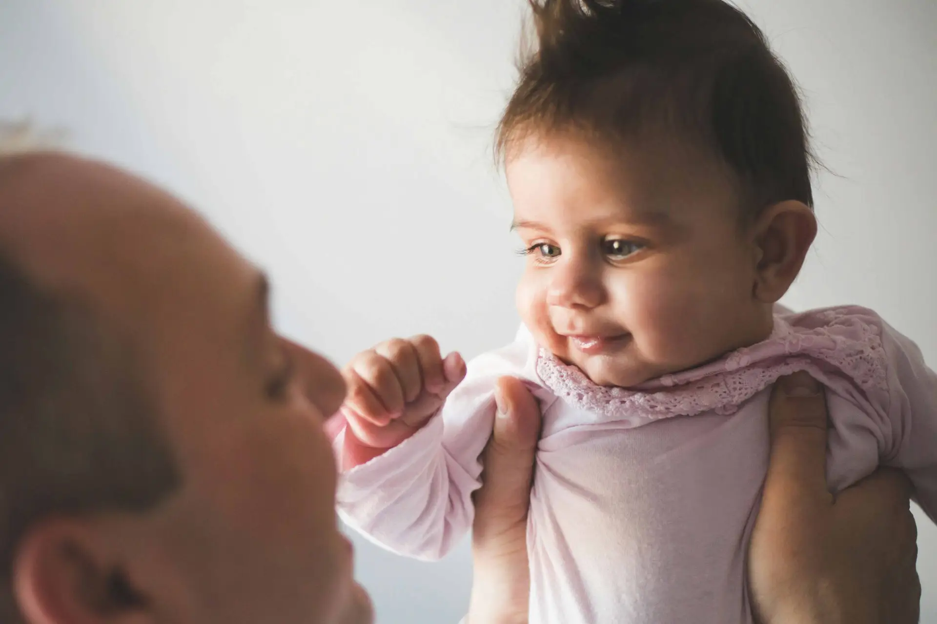 father holding up baby and smiling
