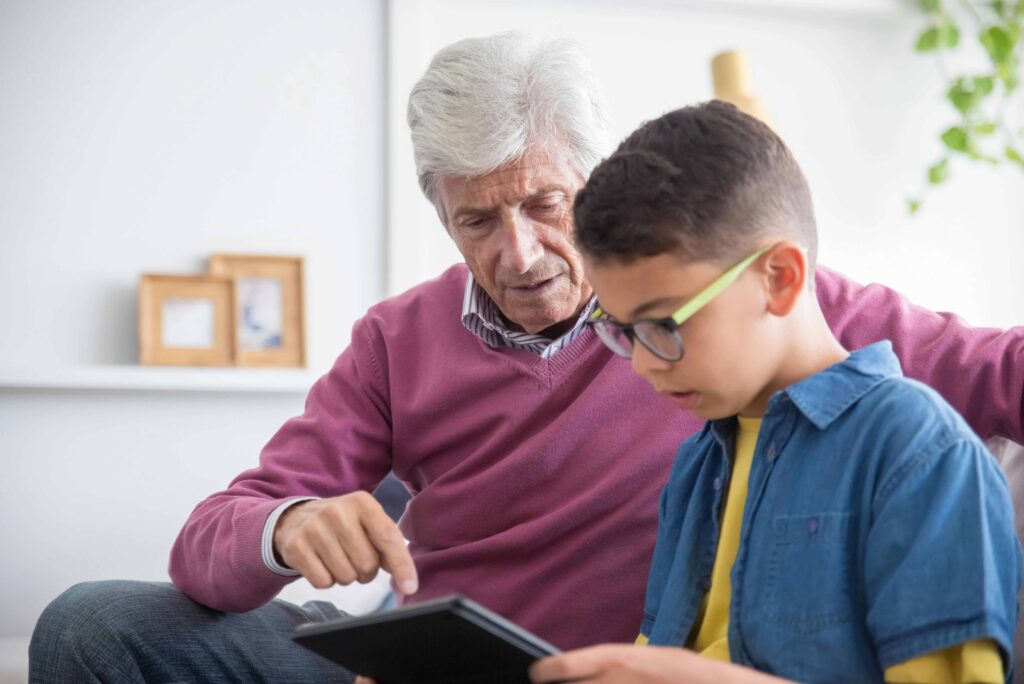 grandad with grandson looking at tablet screen together
