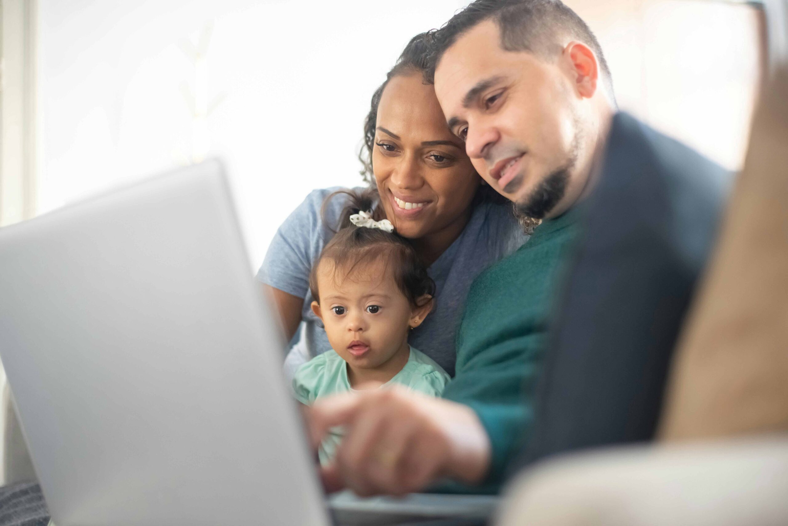 mum dad and child looking at laptop screen smiling