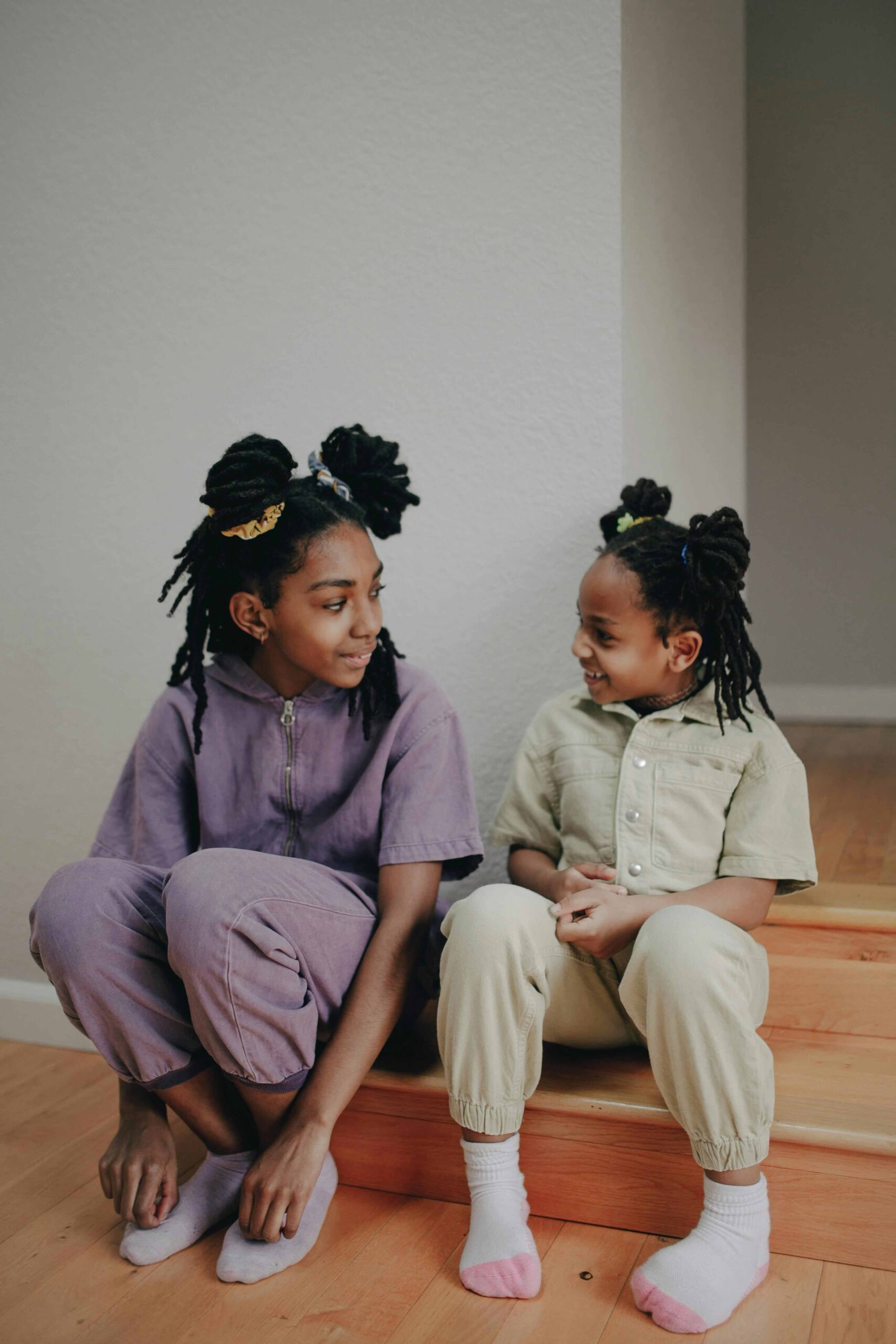 sisters sitting on step smiling looking at each other