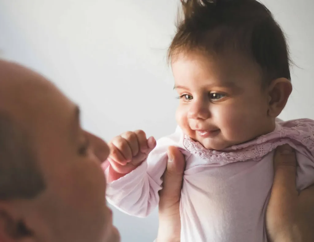 father holding up baby and smiling