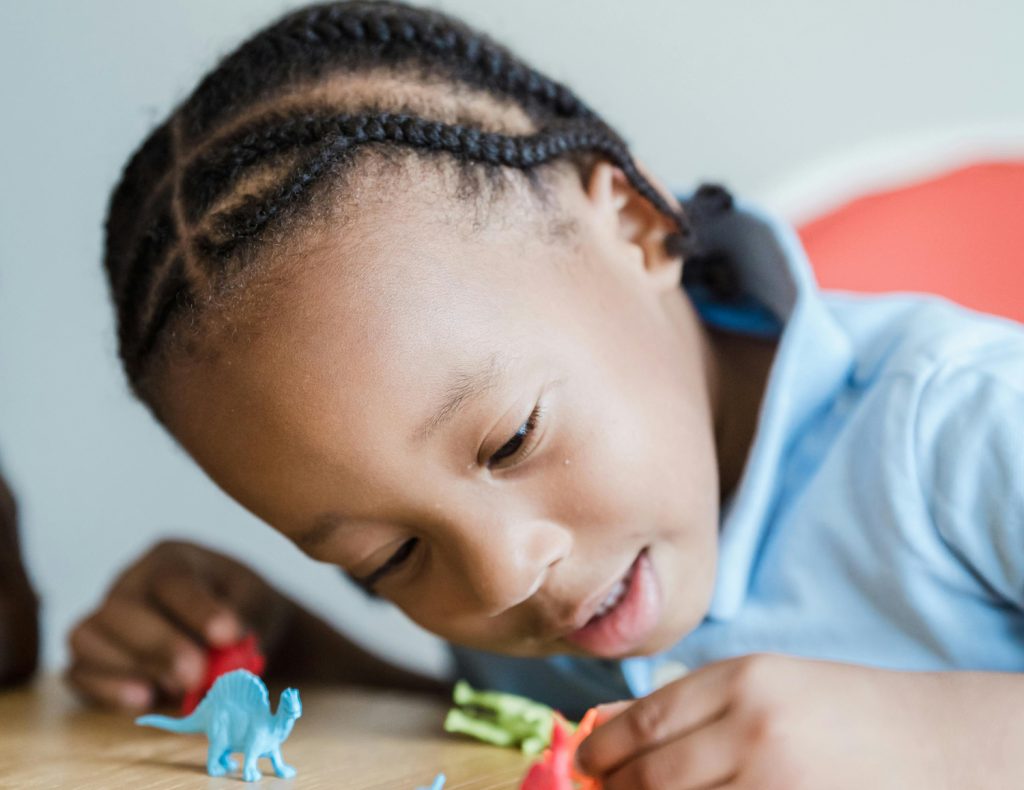 young primary school child playing with dinosaur figurines