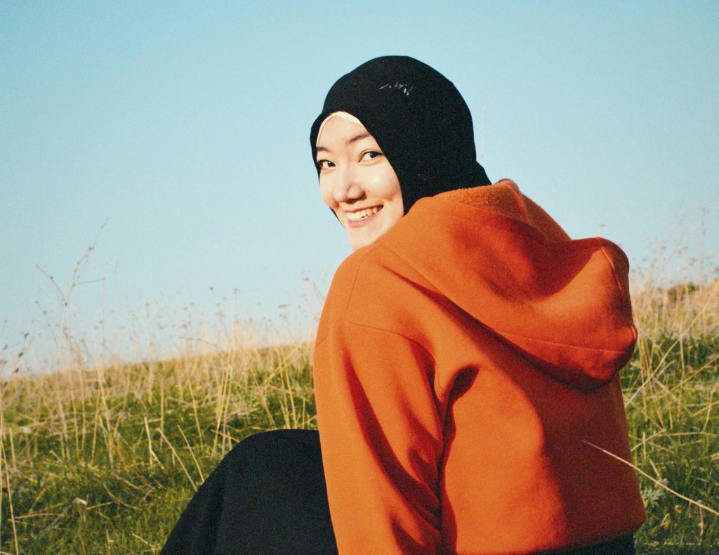 young smiling woman sitting outside on grass